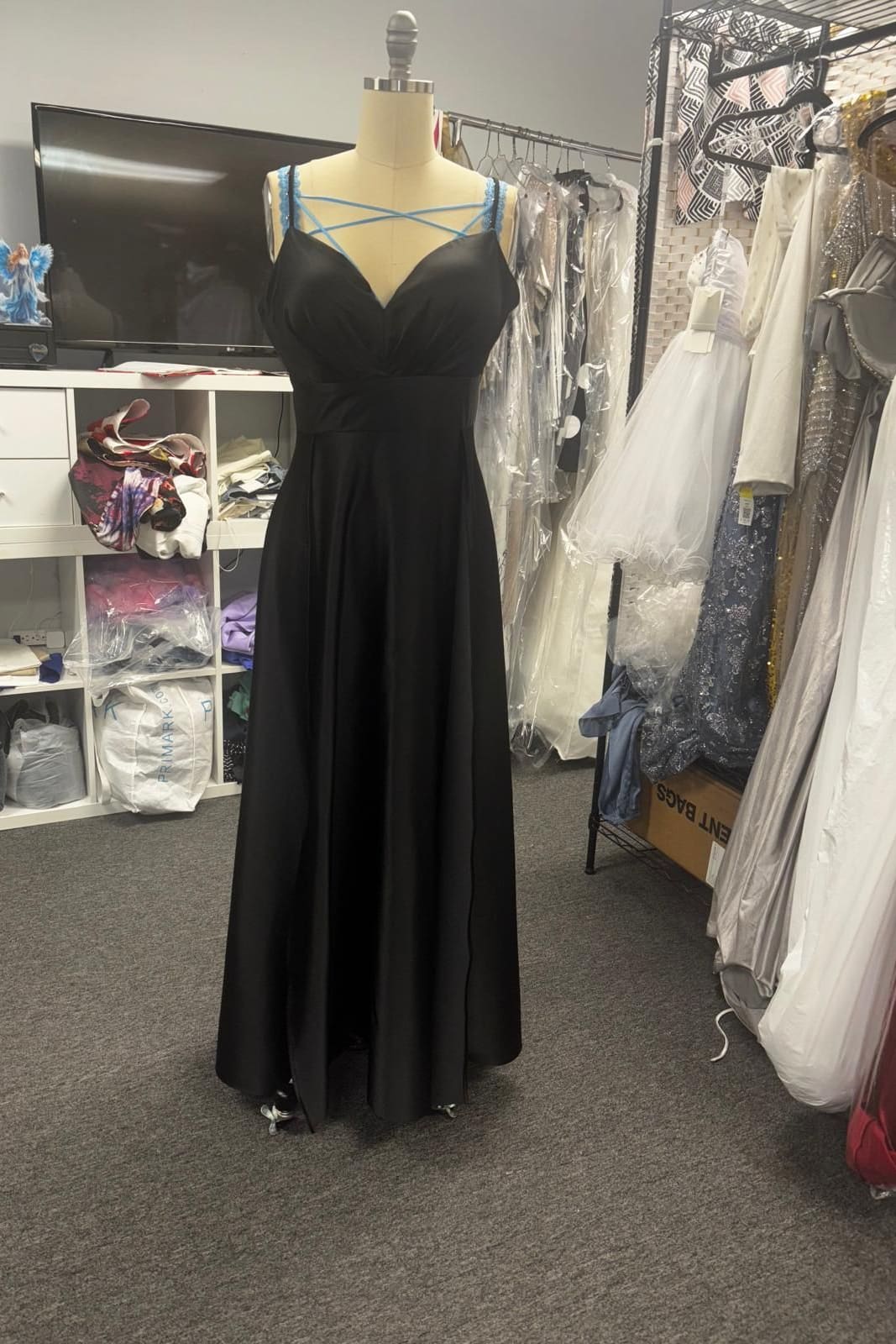 Black satin evening gown with a draped V neckline and fine blue straps on a dress form