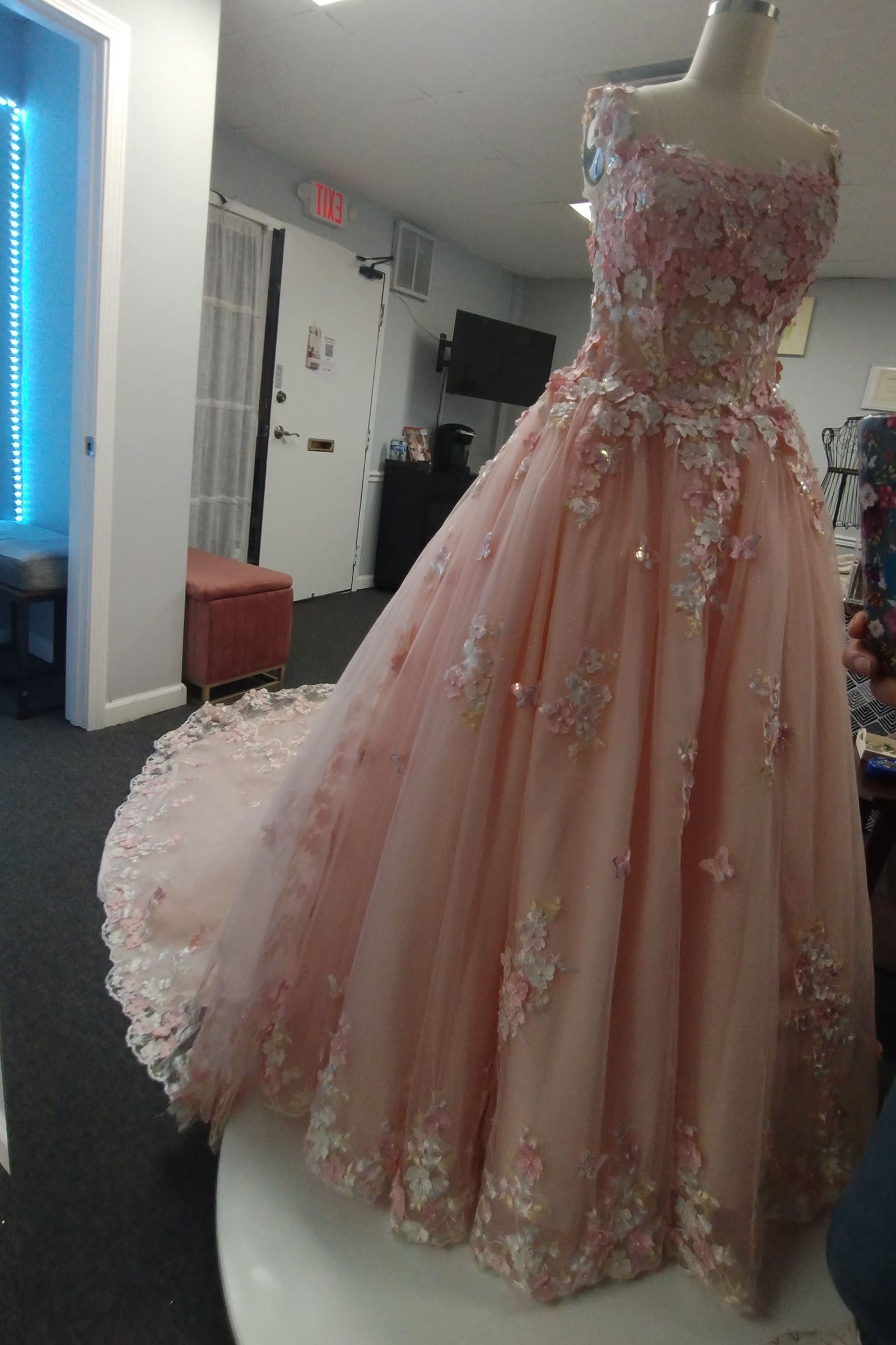 Blush pink ball gown covered in floral appliqués on a turntable
