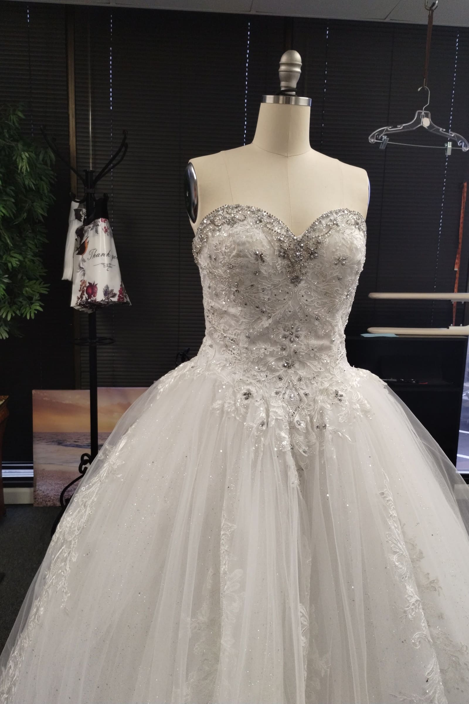Strapless white ball gown with a crystal-beaded sweetheart bodice on a dress form