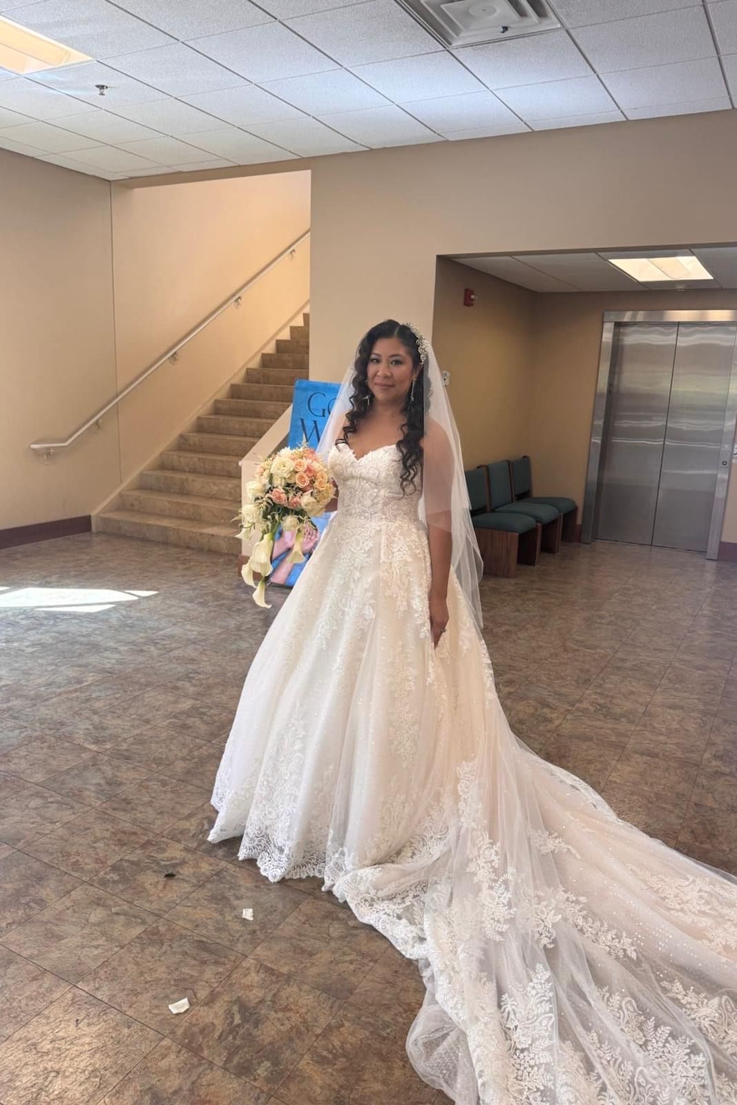 Bride in a lace ball gown with a long train, holding her bouquet