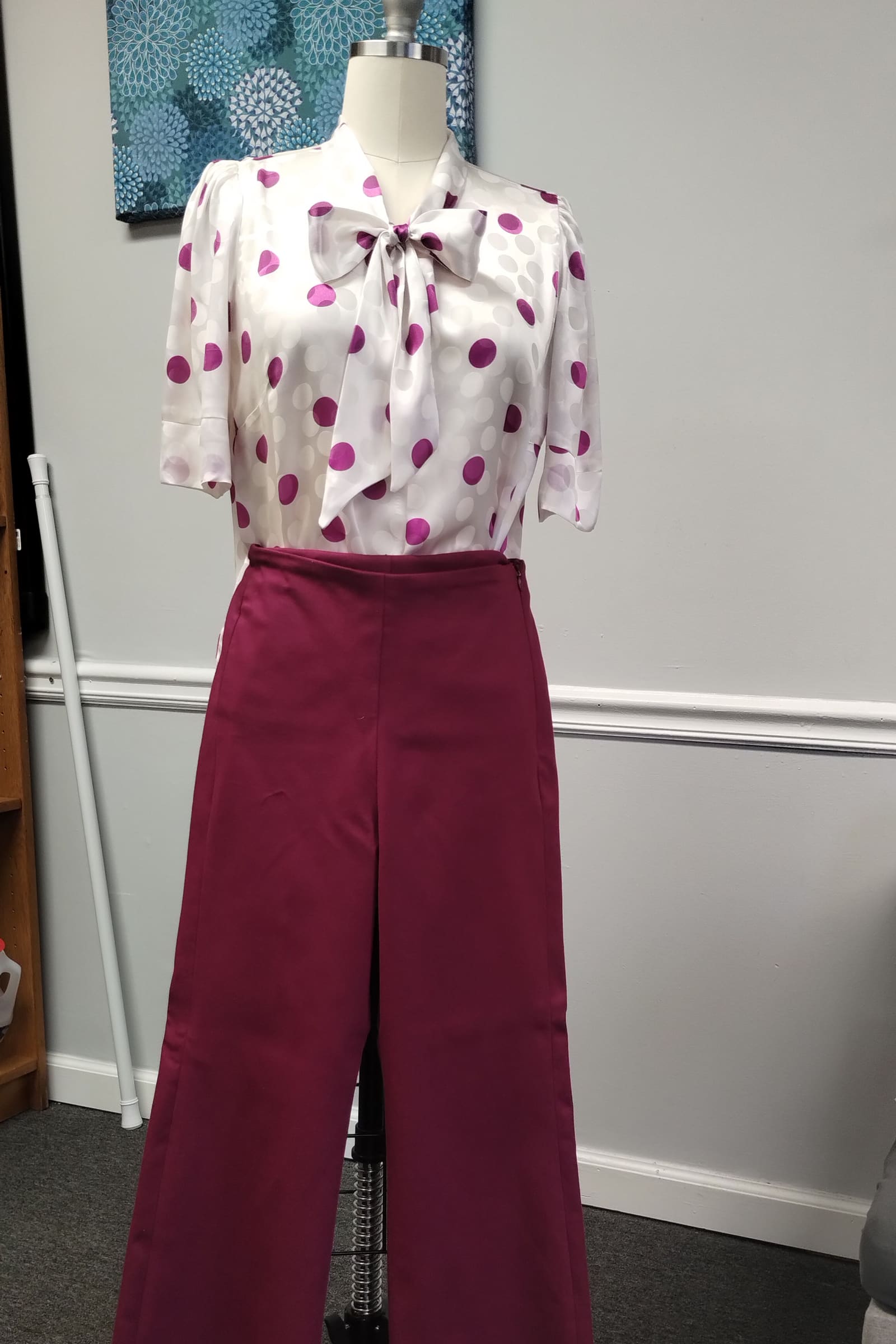 Burgundy wide-leg trousers with a polka-dot bow blouse on a dress form
