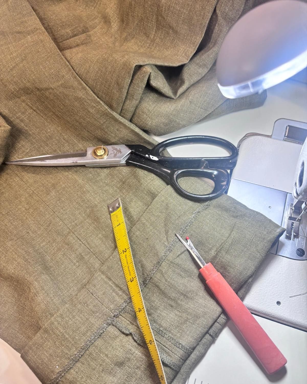 Tape measure, shears and a seam ripper on linen beside the sewing machine