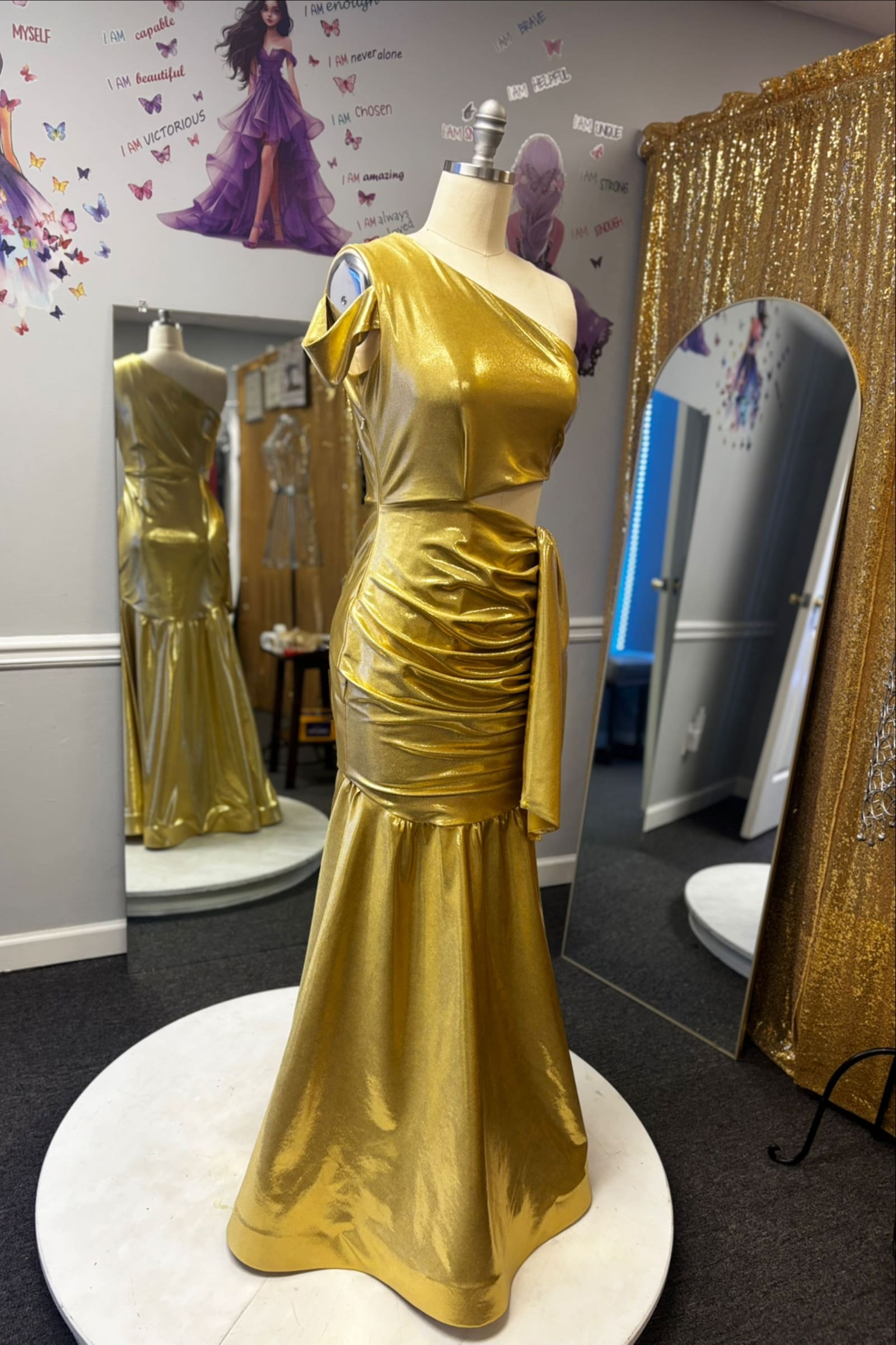 Gold satin one-shoulder mermaid gown on a turntable