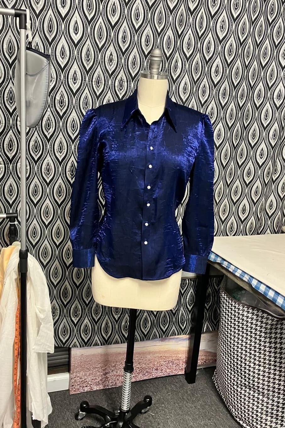 Navy satin shirt with a pointed collar and buttoned cuffs on a dress form