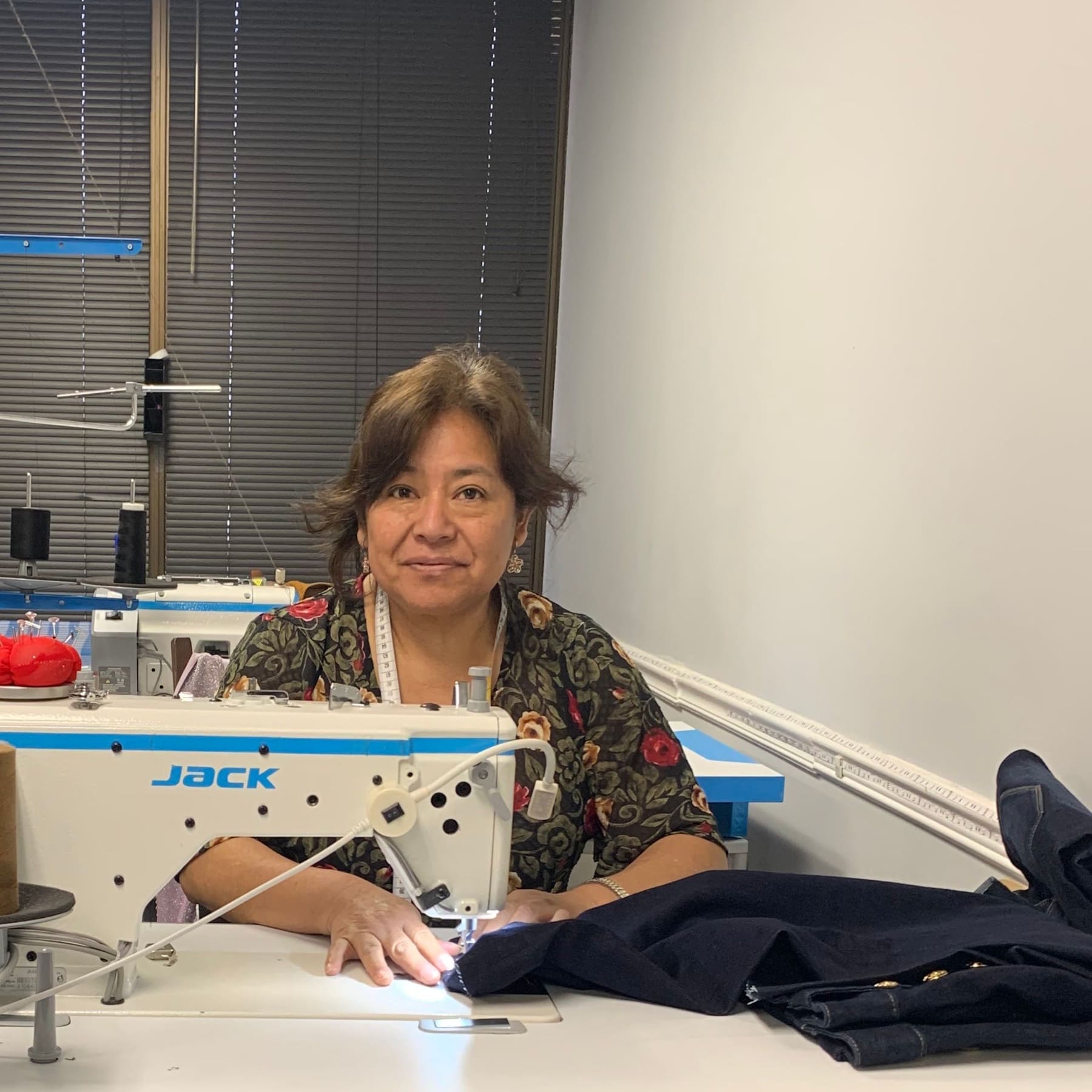 Yolanda Chauca at her sewing machine in the atelier, a dark jacket under the needle
